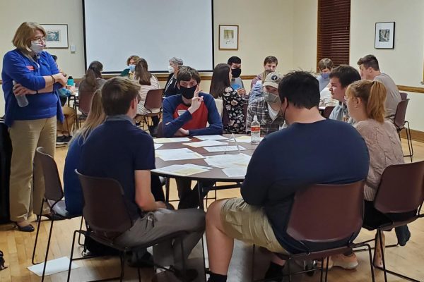 Three tables of students discuss U.S. energy issues under the watchful eye of Catt Center director Karen Kedrowski,.