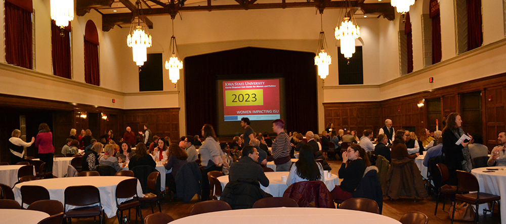 Reception guests in the Great Hall sitting at white cloth-covered tables and mingling before the start of the 2023 Women Impacting ISU calendar reception.