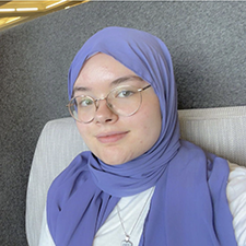 Young woman wearing wire-framed glasses, white clothing and a light purple hijab